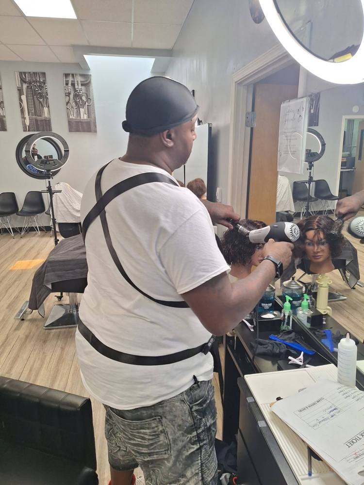 Dave at his station in barber college, styling hair on a practice head
