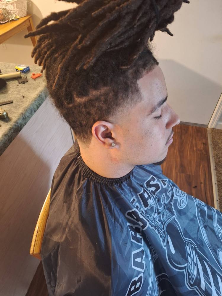 Side view of locs with a taper fade around the ear